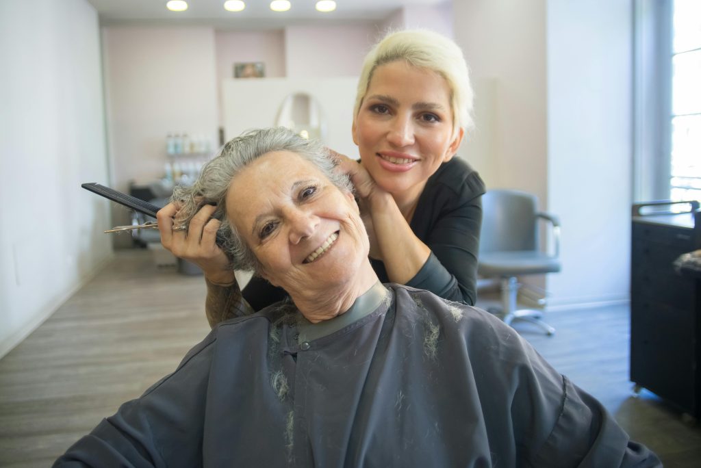 Smiling senior woman in a hair salon getting her hair done by a stylist in Portugal.